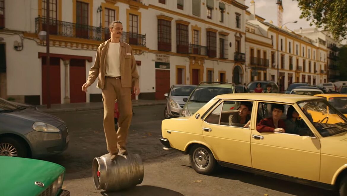男子推著Cruzcampo® 啤酒桶，輕鬆地穿行在西維爾石板鋪就的狹窄街道上